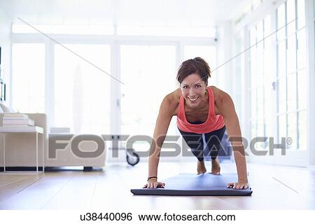 Mid adult woman doing press ups in living room View Large Photo Image Stock Photograph - Mid adult woman doing press ups in living room. Fotosearch