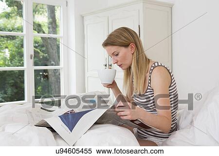 Mid adult woman sitting in bed reading newspaper View Large Photo Image Stock Photography - Mid adult woman sitting in bed reading newspaper. Fotosearch
