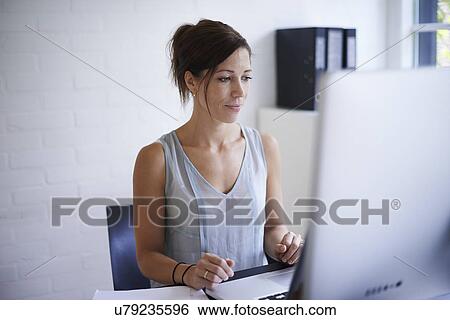 Mid adult woman working from home on computer View Large Photo Image Stock Photograph - Mid adult woman working from home on computer. Fotosearch