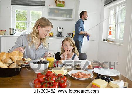 Stock Image - Mother and daughter eating at kitchen table. Fotosearch