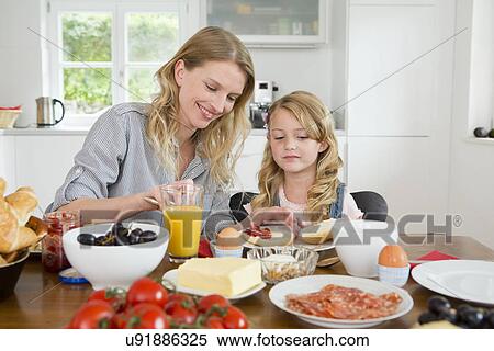 Stock Photography - Mother and daughter eating at kitchen table. Fotosearch