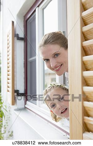 Mother and daughter peering through window View Large Photo Image Stock Image - Mother and daughter peering through window. Fotosearch