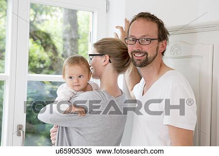 Mother and father looking out of window with baby daughter View Large Photo Image Stock Photography - Mother and father looking out of window with baby daughter. Fotosearch