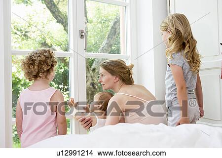 Mother and three daughters looking out of window View Large Photo Image Picture - Mother and three daughters looking out of window. Fotosearch
