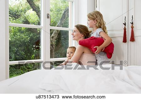Mother and two daughters looking out of window View Large Photo Image Stock Image - Mother and two daughters looking out of window. Fotosearch
