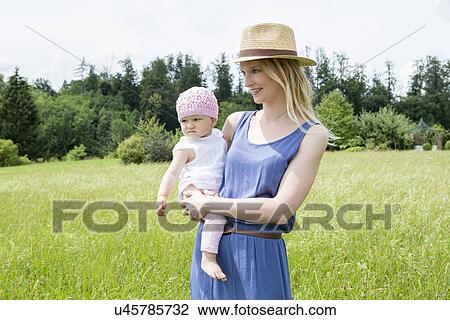 Mother holding baby daughter in field View Large Photo Image Stock Image - Mother holding baby daughter in field. Fotosearch