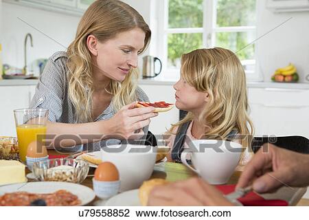 Stock Image - Mother offering daughter some food. Fotosearch
