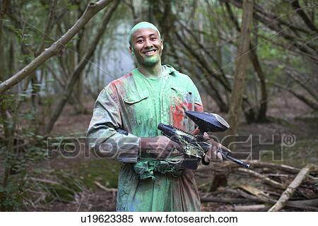 Stock Photography - Paintball player in paintball wear marked with paint. Fotosearch