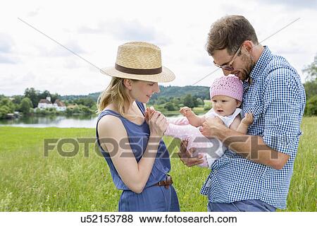 Parents holding baby daughter in field View Large Photo Image Stock Photo - Parents holding baby daughter in field. Fotosearch