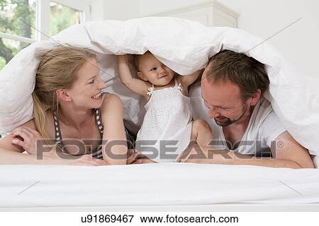 Parents playing with baby daughter under duvet View Large Photo Image Stock Photo - Parents playing with baby daughter under duvet. Fotosearch