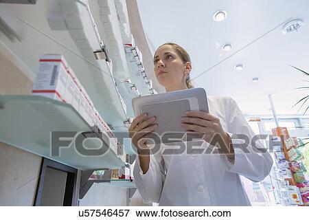 Stock Photo - Pharmacist in pharmacy holding digital tablet. Fotosearch