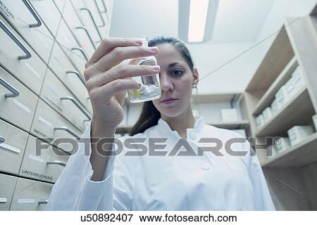 Stock Photo - Pharmacist in pharmacy holding medicine in hand. Fotosearch