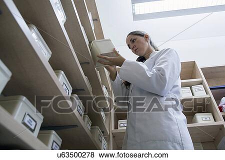 Stock Photo - Pharmacist in pharmacy holding storage tin. Fotosearch