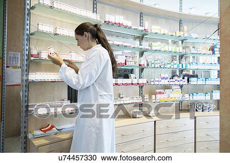 Pharmacist in pharmacy looking at medicine box View Large Photo Image Stock Image - Pharmacist in pharmacy looking at medicine box. Fotosearch