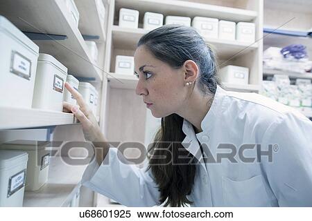 Pharmacist in pharmacy looking at storage tin View Large Photo Image Stock Photography - Pharmacist in pharmacy looking at storage tin. Fotosearch