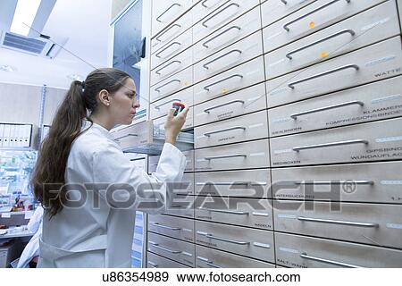 Pharmacist in pharmacy opening medicine file drawer View Large Photo Image Stock Photo - Pharmacist in pharmacy opening medicine file drawer. Fotosearch