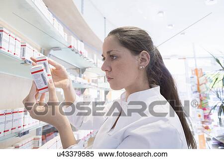 Pharmacist in pharmacy reading medicine box View Large Photo Image Stock Photography - Pharmacist in pharmacy reading medicine box. Fotosearch