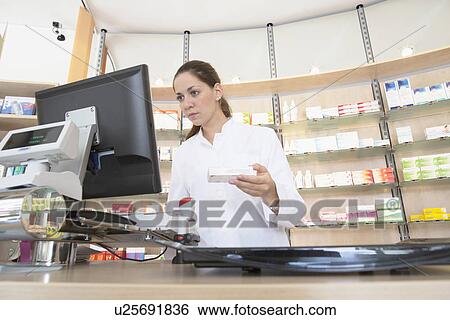 Pharmacist in pharmacy using computer View Large Photo Image Stock Photograph - Pharmacist in pharmacy using computer. Fotosearch