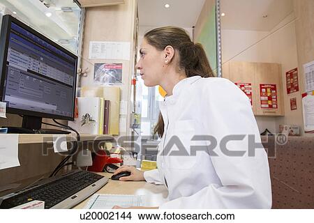 Picture - Pharmacist in pharmacy using desktop computer. Fotosearch