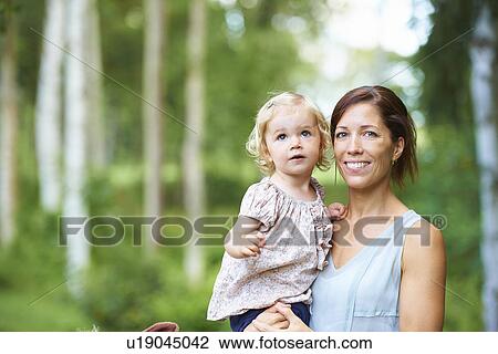 Stock Image - Portrait mid adult woman and toddler daughter in garden. Fotosearch