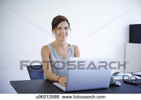 Stock Photo - Portrait mid adult woman working from home on laptop. Fotosearch