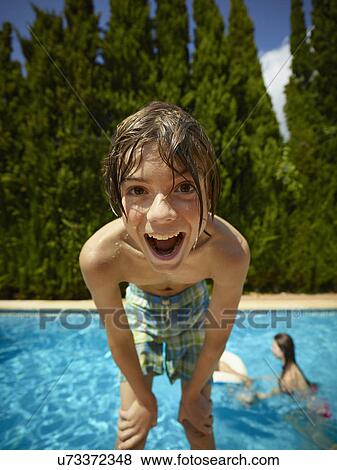 Stock Photo - Portrait of boy leaning forward in front of swimming pool, Majorca, Spain. Fotosearch