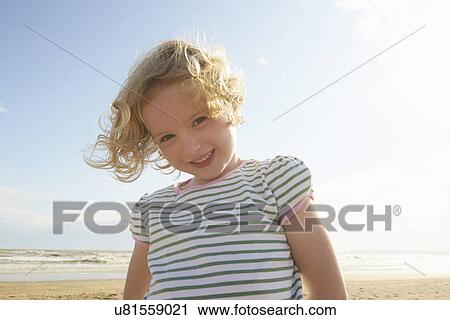 Stock Image - Portrait of cute girl on beach, Camber Sands, Kent, UK. Fotosearch