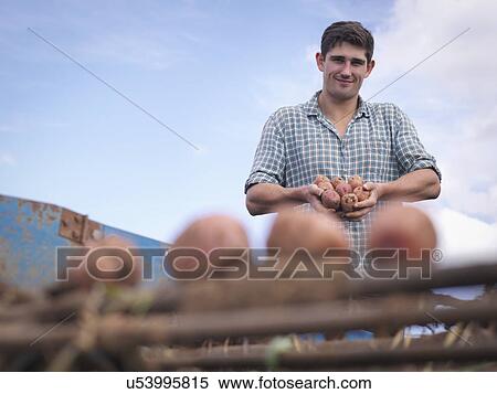 Stock Photography - Portrait of farmer holding crop of organic potatoes. Fotosearch