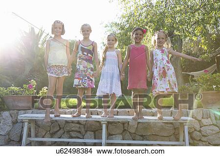 Picture - Portrait of five girls standing on garden bench. Fotosearch
