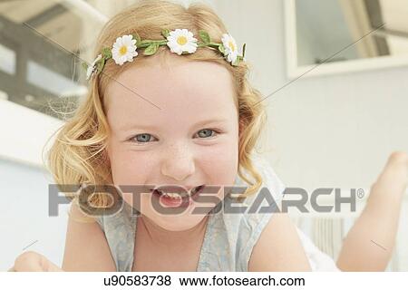 Stock Photo - Portrait of girl in daisy chain lying on holiday apartment seat. Fotosearch