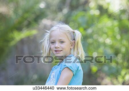 Stock Image - Portrait of girl looking away in garden. Fotosearch