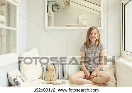 Stock Image - Portrait of girl looking sideways in holiday apartment porch. Fotosearch