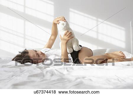 Portrait of girl lying on bed petting toy rabbit View Large Photo Image Stock Photo - Portrait of girl lying on bed petting toy rabbit. Fotosearch