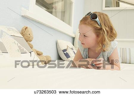 Portrait of girl lying on holiday apartment seat with teddy bear View Large Photo Image Stock Image - Portrait of girl lying on holiday apartment seat with teddy bear. Fotosearch