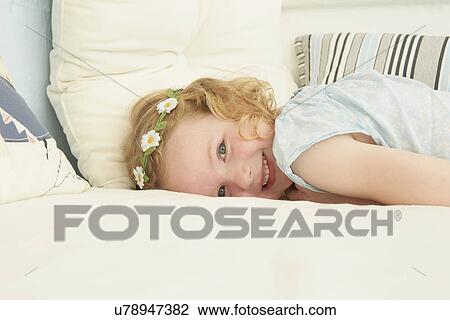 Stock Image - Portrait of girl lying on seat in holiday apartment. Fotosearch