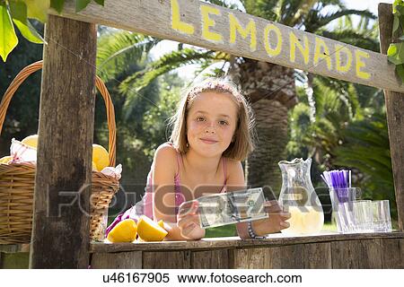 Stock Photography - Portrait of girl on lemonade stand holding up one hundred dollar bill. Fotosearch