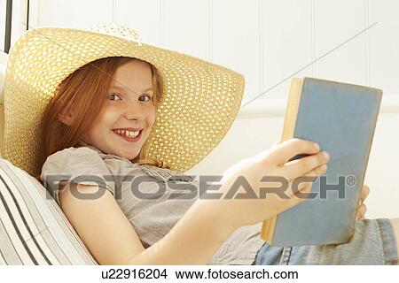 Picture - Portrait of girl reading book in holiday apartment porch. Fotosearch
