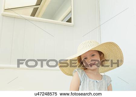 Stock Photography - Portrait of girl with sunhat on in holiday apartment. Fotosearch