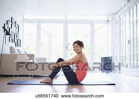 Portrait of mid adult woman on yoga mat in living room View Large Photo Image Stock Image - Portrait of mid adult woman on yoga mat in living room. Fotosearch
