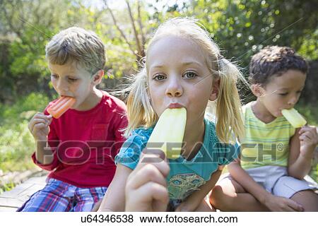 Portrait of three children in garden eating ice lollies View Large Photo Image Stock Photo - Portrait of three children in garden eating ice lollies. Fotosearch