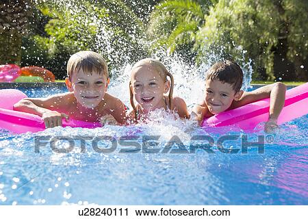 Portrait of three children splashing on inflatable mattress in garden swimming pool View Large Photo Image Stock Image - Portrait of three children splashing on inflatable mattress in garden swimming pool. Fotosearch