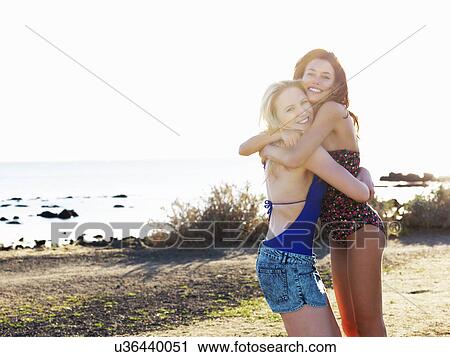 Stock Image - Portrait of two young women friends hugging on beach, Williamstown, Melbourne, Australia. Fotosearch