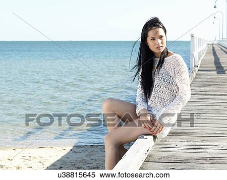 Stock Photography - Portrait of young woman sitting on pier, Port Melbourne, Melbourne, Victoria, Australia. Fotosearch