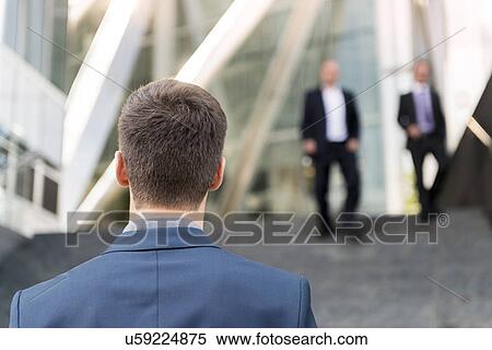 Rear view of young businessman outside office building, London, UK View Large Photo Image Stock Photography - Rear view of young businessman outside office building, London, UK. Fotosearch