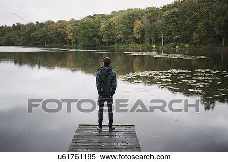 Rear view of young man standing on river pier View Large Photo Image Stock Photography - Rear view of young man standing on river pier. Fotosearch