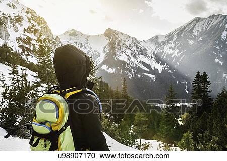 Stock Image - Rear view of young woman gazing at mountains, Hundsarschjoch, Vils, Bavaria, Germany. Fotosearch