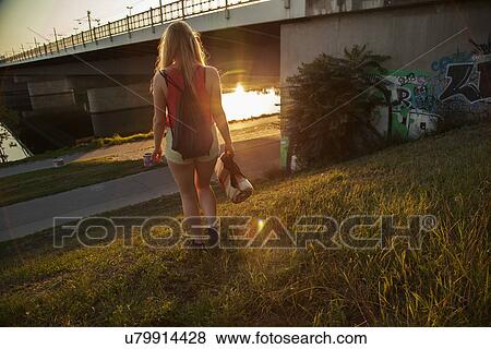 Rear view of young woman walking near bridge and riverside View Large Photo Image Stock Photo - Rear view of young woman walking near bridge and riverside. Fotosearch