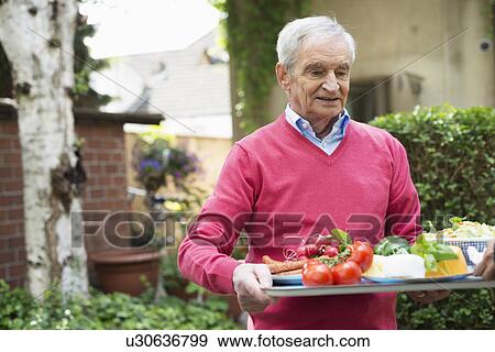 Senior man carrying tray of fresh food View Large Photo Image Stock Photo - Senior man carrying tray of fresh food. Fotosearch