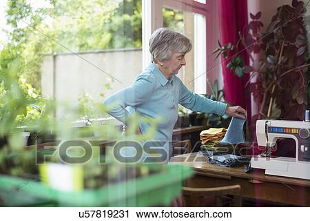 Senior woman choosing fabric by sewing machine View Large Photo Image Stock Image - Senior woman choosing fabric by sewing machine. Fotosearch