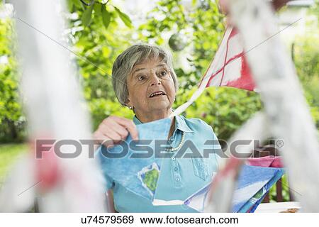 Senior woman hanging up bunting View Large Photo Image Stock Photo - Senior woman hanging up bunting. Fotosearch